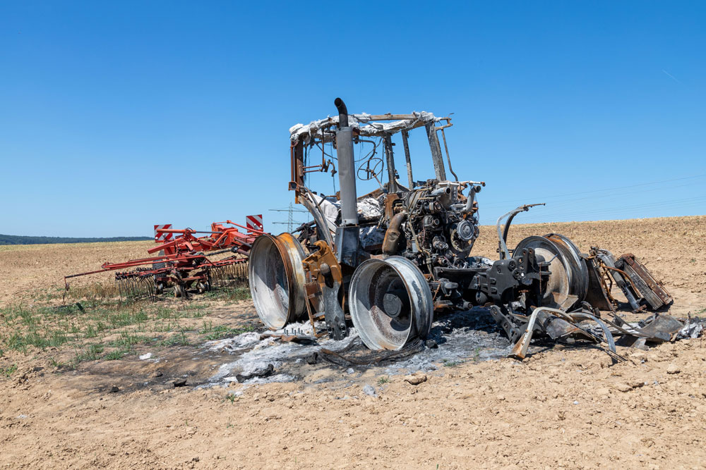 Traktor mit Anhänger auf einem Feld durch Hitzestau in Brand geraten